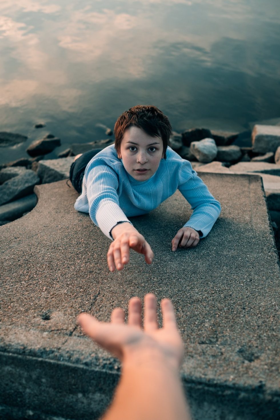 Foto de adolescente estirando su mano para sujetar a otro